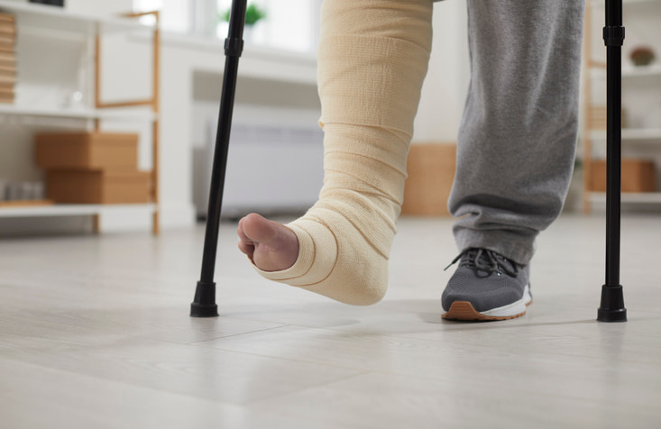 Person with bandaged ankle using crutches after ankle replacement in Millsboro & Seaford, DE